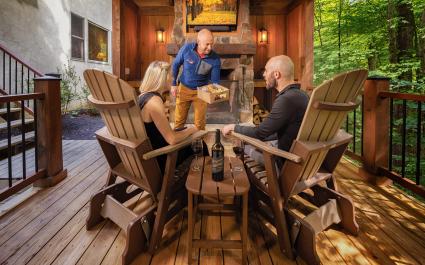 man and woman in gliding chairs. A staff member hands them a charcuterie box