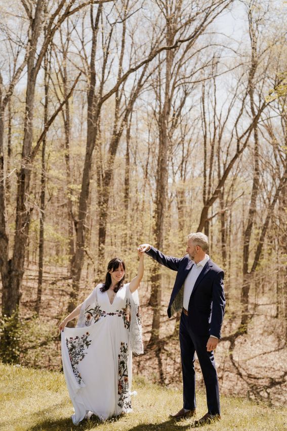 Groom twirls bride, forest in background