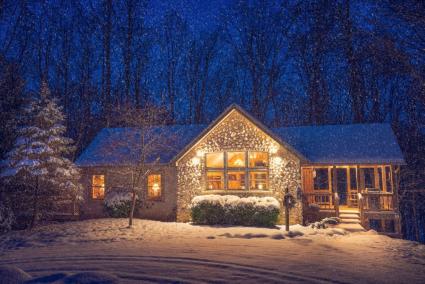 Ravine's Edge cabin at night with snowfall.